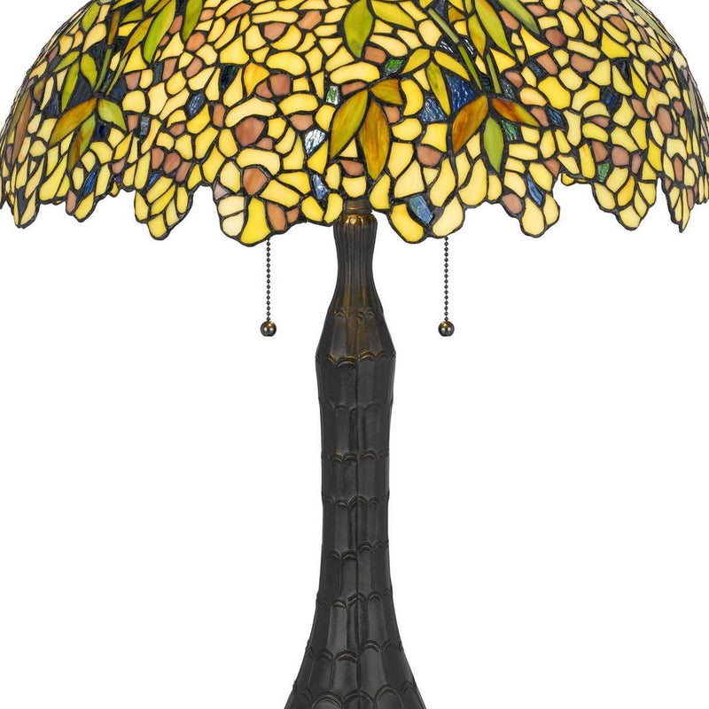 Close-up of yellow-green stained glass dome lamp shade and dark bronze base stem