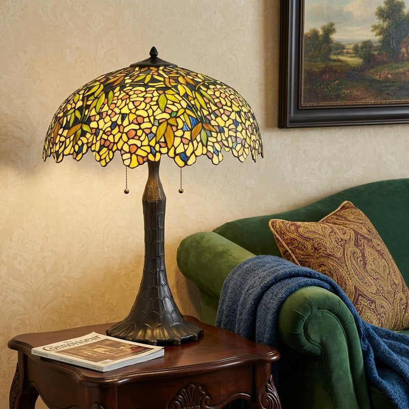 Stained glass table lamp with yellow-green dome shade on a wooden side table