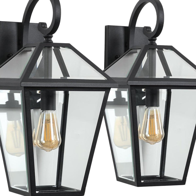 Close-up of two black outdoor hanging lantern lights with clear glass panels and bulbs