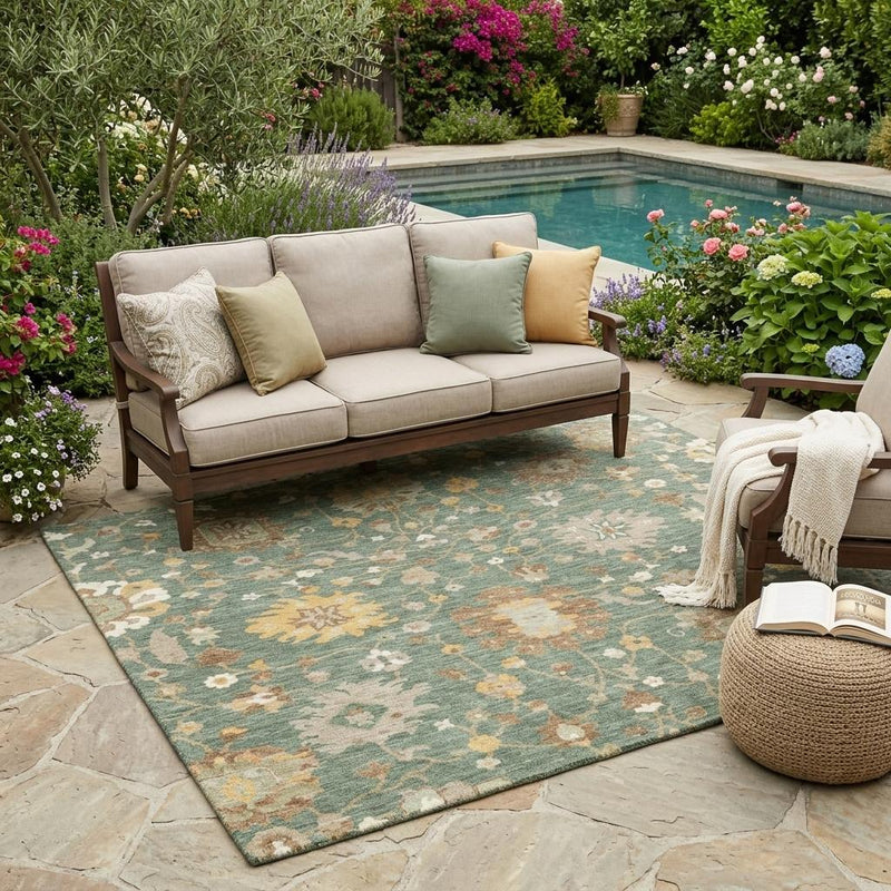 Teal-green floral area rug laid outdoors on stone patio with medallion and vine motifs