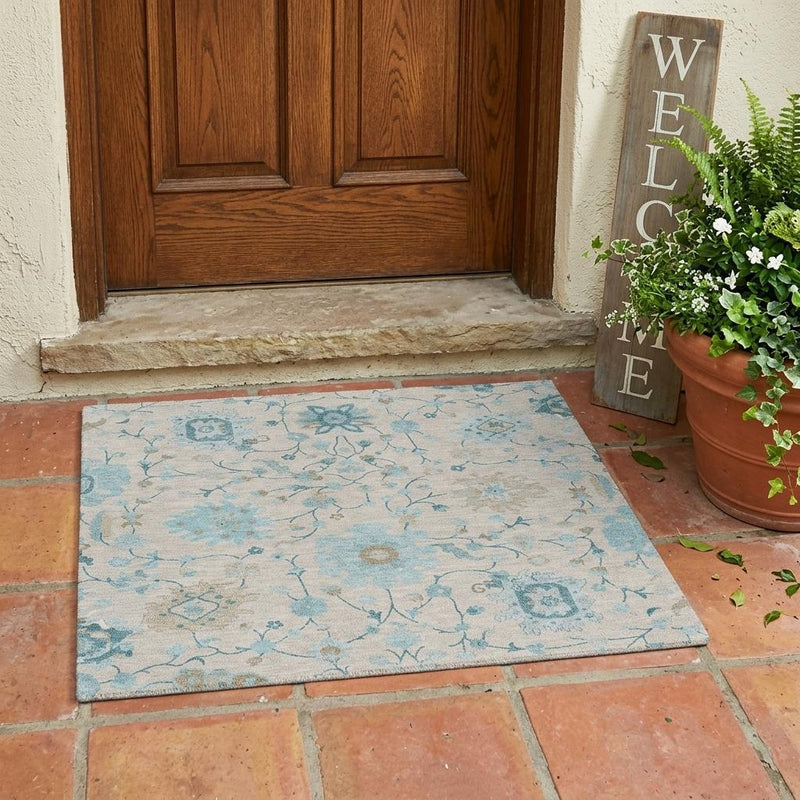 Light blue and ivory floral outdoor area rug on terracotta tile floor