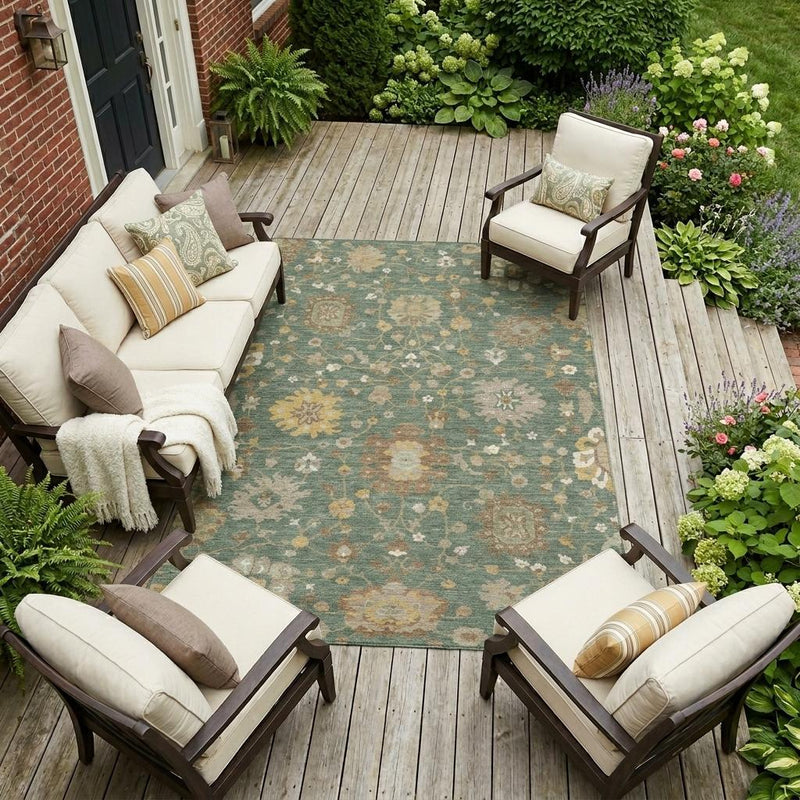 Green and beige floral area rug laid outdoors on a wooden deck, full top view.