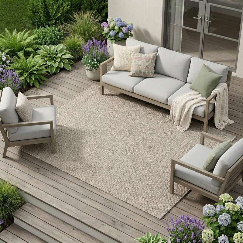 Beige indoor outdoor area rug with textured flat weave, laid on outdoor patio