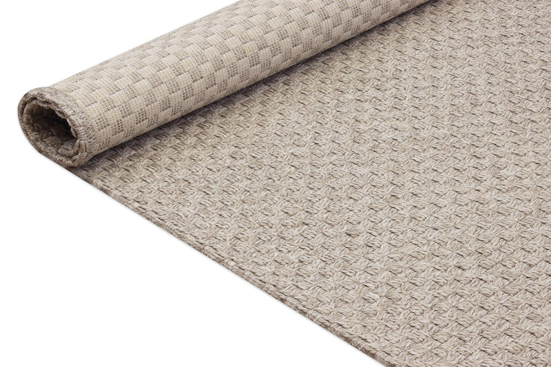 Beige indoor outdoor area rug, rolled edge showing tight woven texture