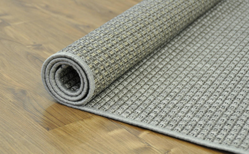Rolled gray indoor/outdoor area rug showing textured surface and low-profile edge