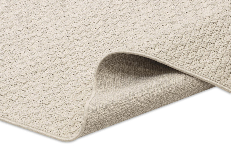 Beige area rug corner with stitched edge and looped surface texture.