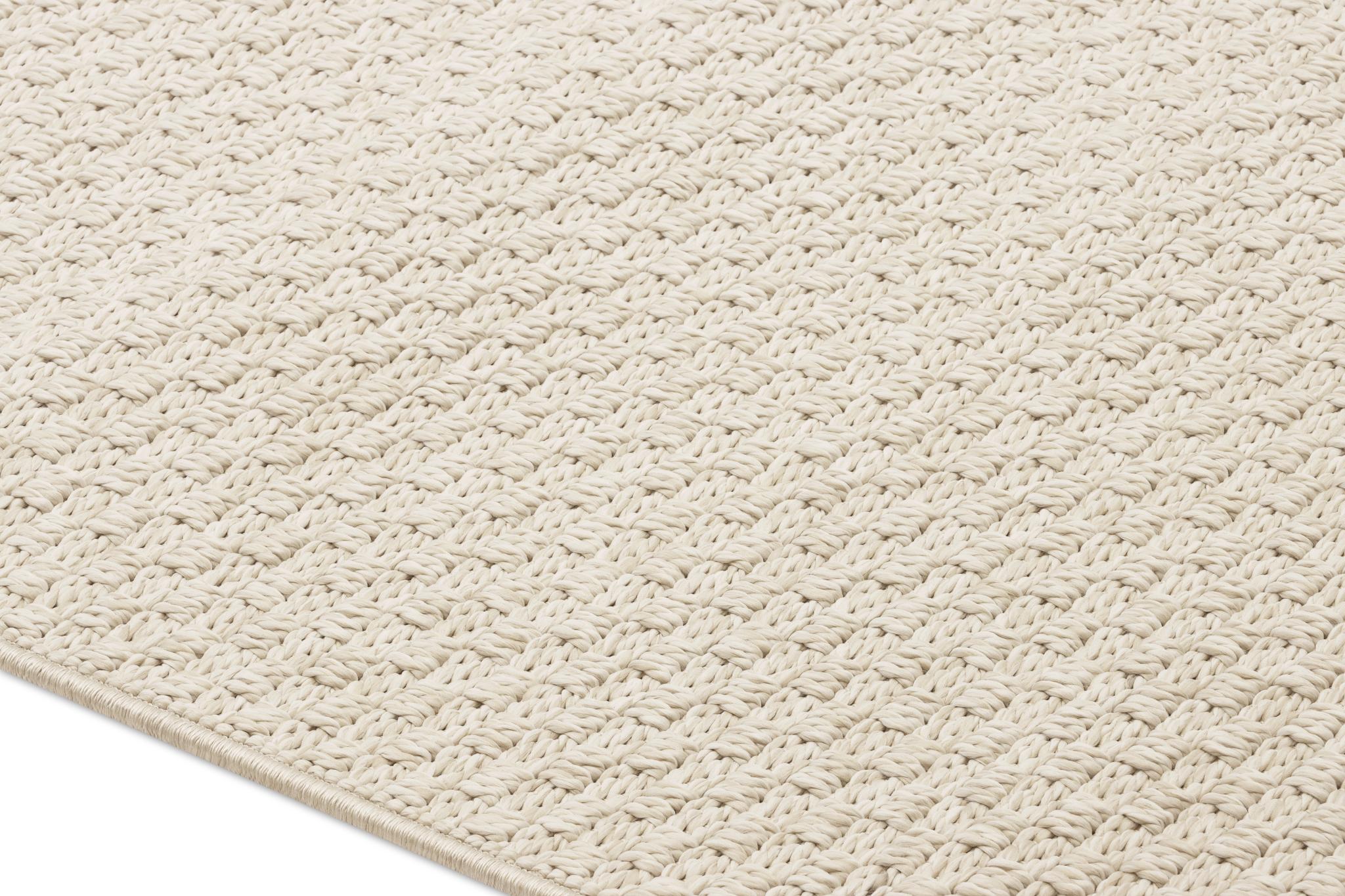 Beige area rug close-up showing dense looped weave texture.
