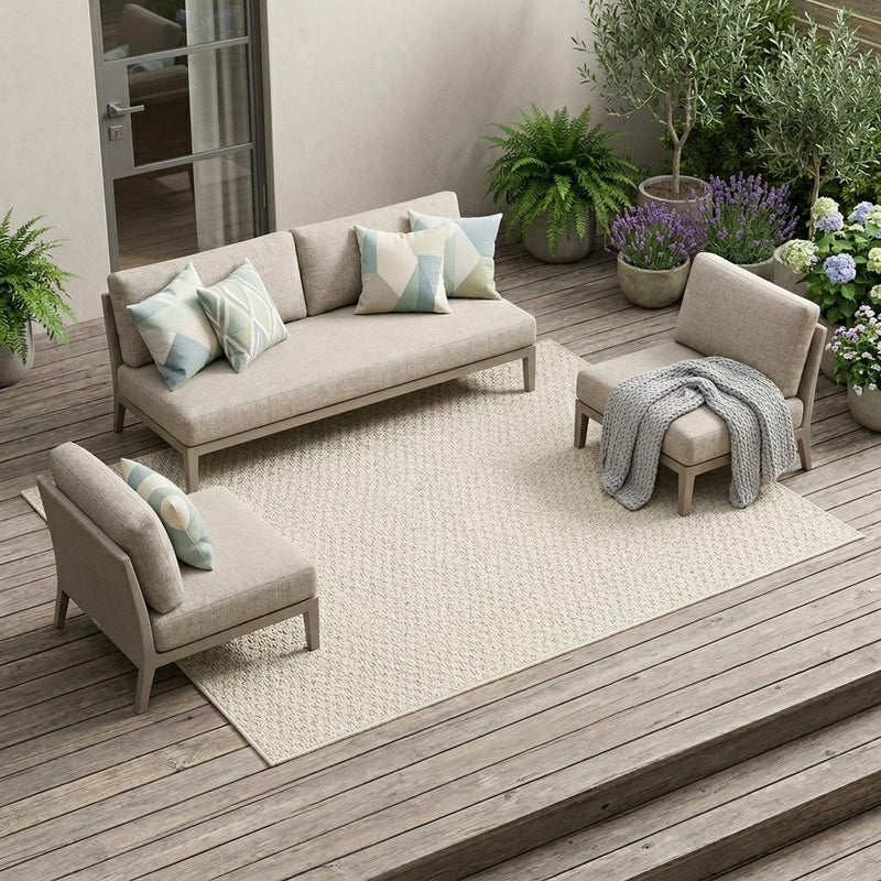 Beige indoor outdoor area rug with looped texture, set on outdoor flooring.