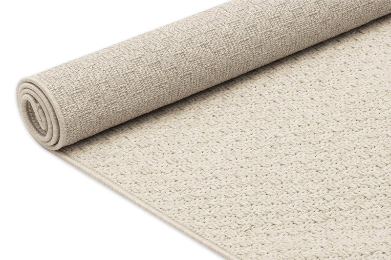 Beige area rug rolled up, showing looped texture and thick flat pile.