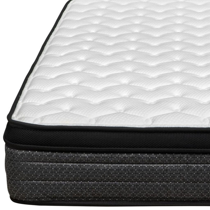 Close-up foam mattress edge with white quilted top, dark charcoal fabric and black trim