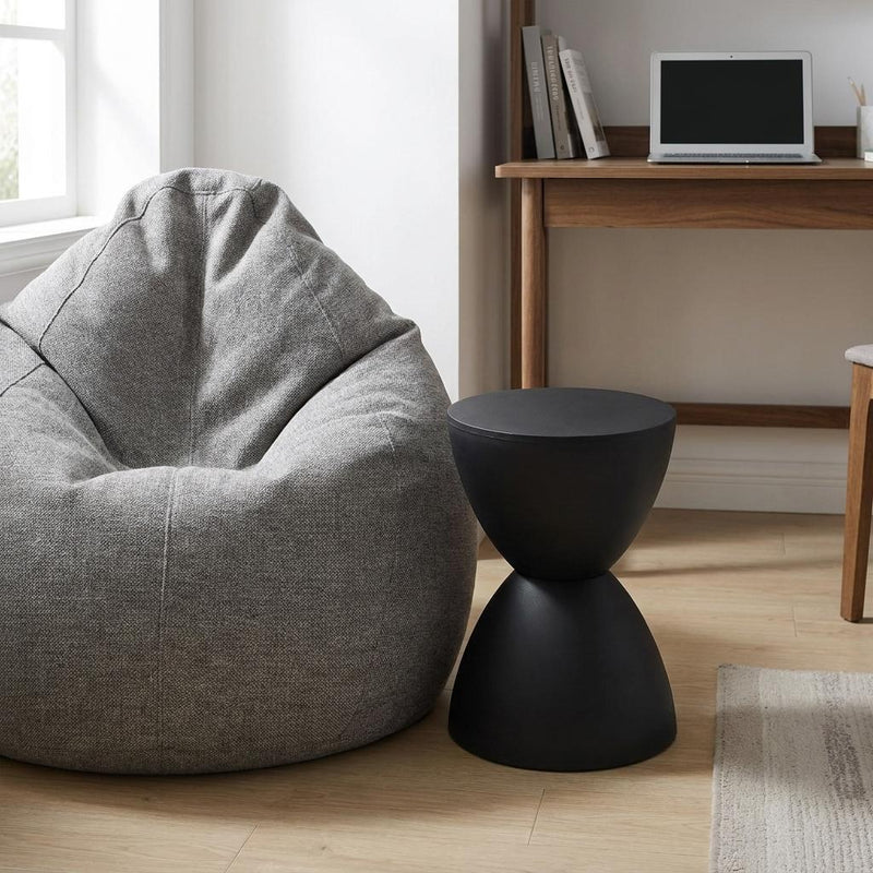 Black hourglass side table, close view of round top and tapered pedestal base.