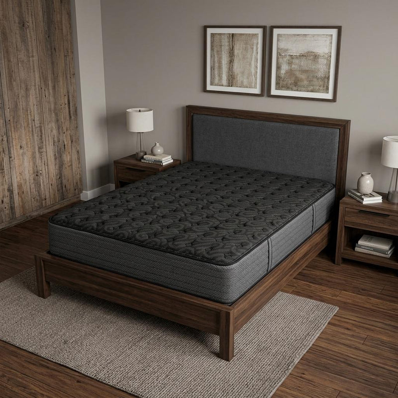 Dark black extra firm hybrid mattress on a wooden bed frame with tufted top.