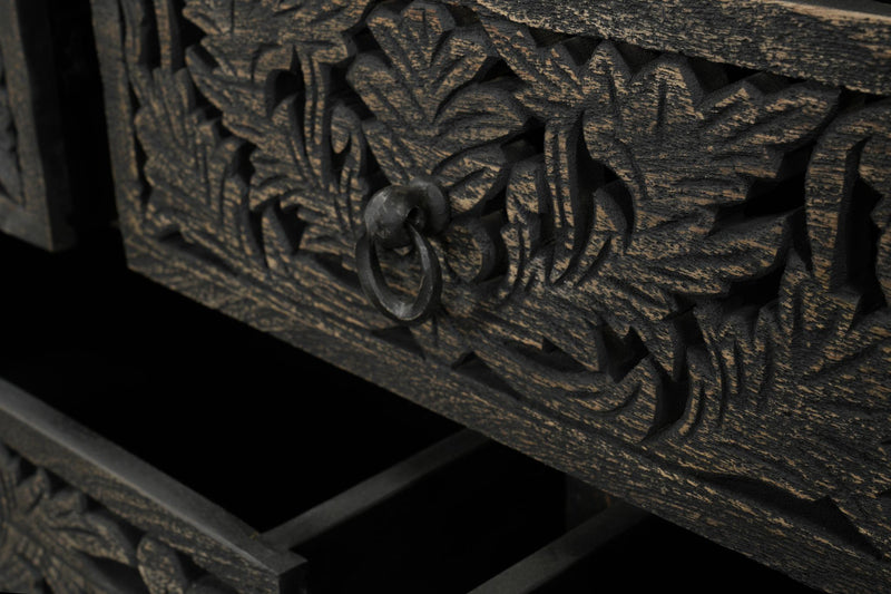 Close-up of ornate floral carving on a dark wood drawer face