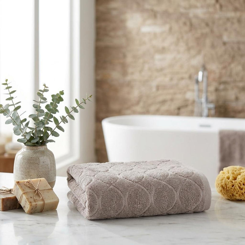 Light brown jacquard bath towel rolled on countertop with circular texture