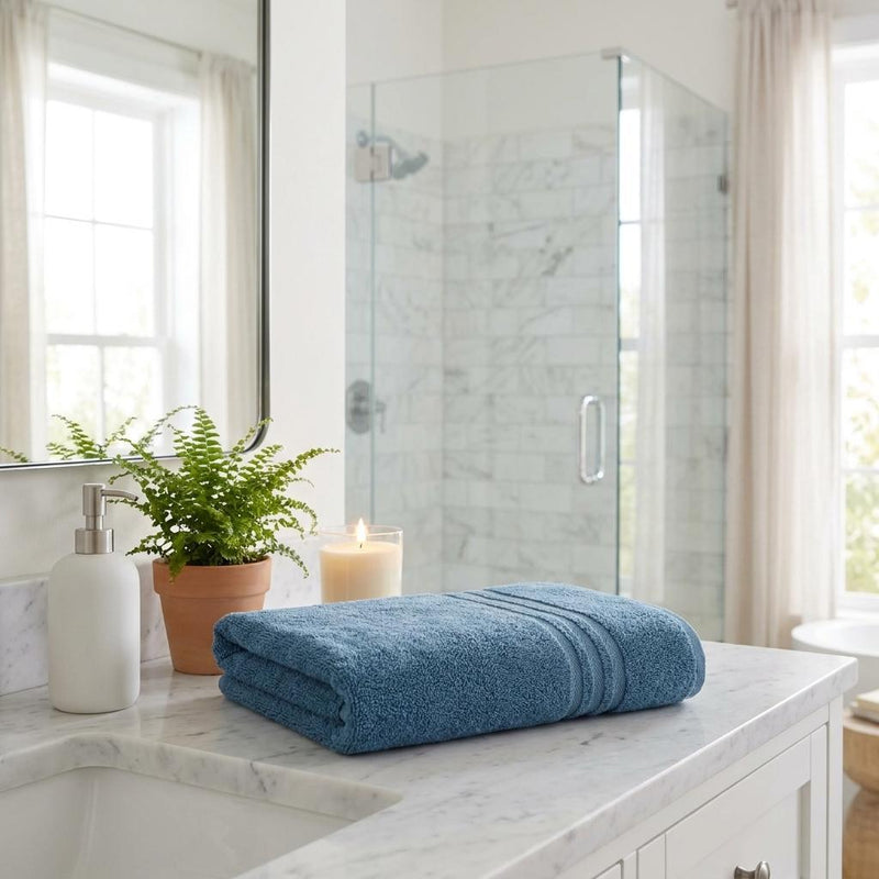 Folded aqua blue bath sheet towel with striped bands on bathroom counter