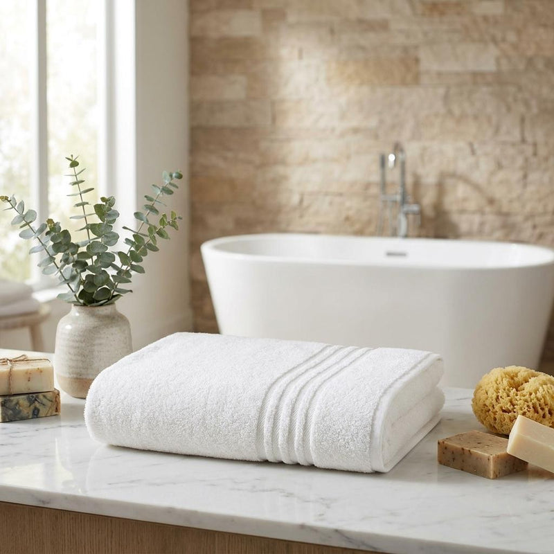 Beige Turkish cotton bath sheet towel, rolled and folded with stitched border