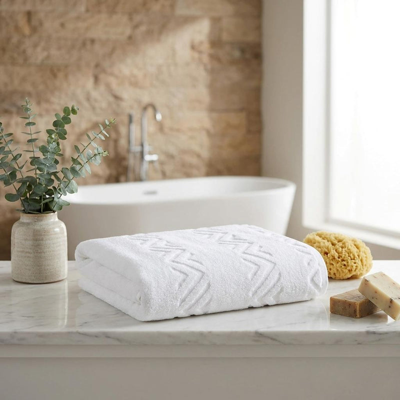 White jacquard bath sheet folded on counter, embossed chevron zigzag pattern