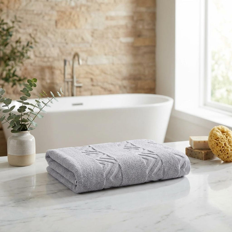 Folded light gray jacquard bath towel with chevron pattern on bathroom counter