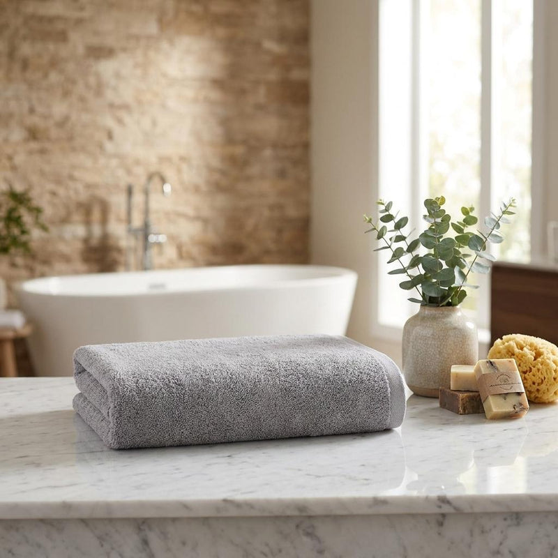 Folded light gray Turkish cotton bath towel on a marble counter near a bathtub