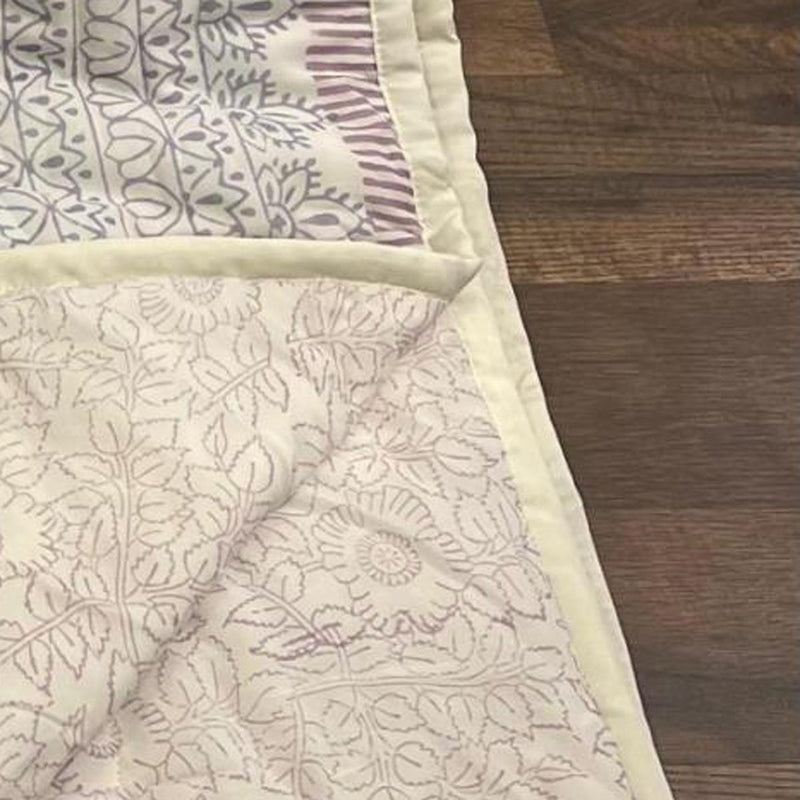Corner of cream floral comforter with light sage piping