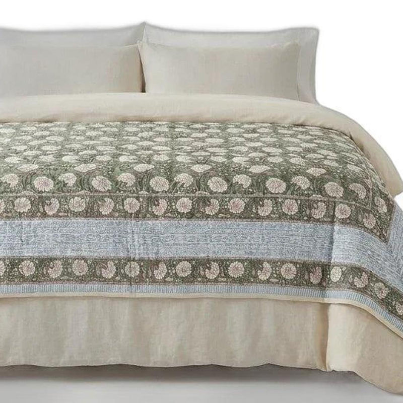 Cream cotton comforter close-up with green floral medallions and blue-gray border