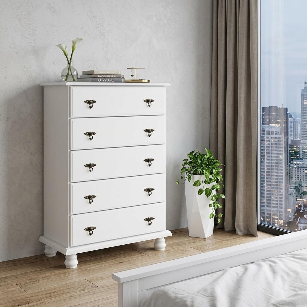 White five-drawer dresser with ornate metal knobs, shown in a room corner.
