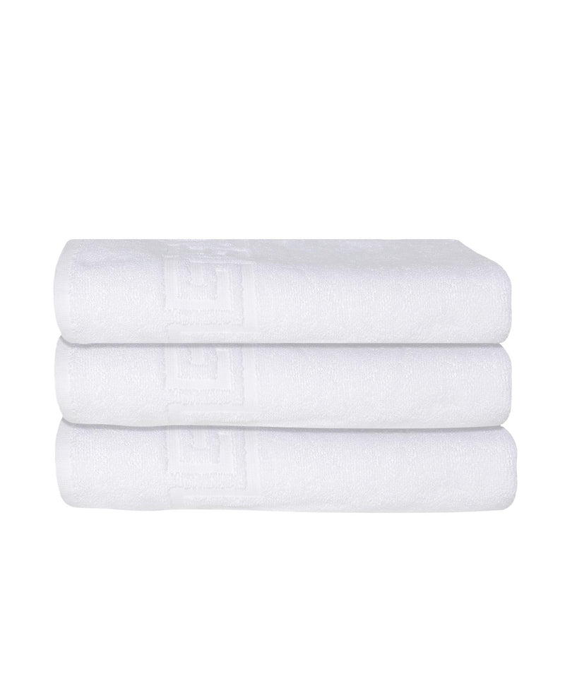 Stack of three white Turkish cotton bath towels with Greek key border visible on ends