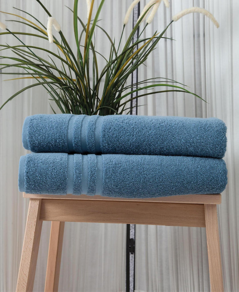 Stack of two aqua blue bath towels on a light wooden stool, striped accents
