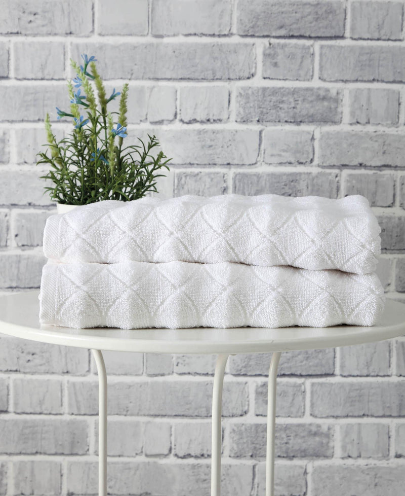White bath towel stack with geometric diamond pattern, folded and ready to use