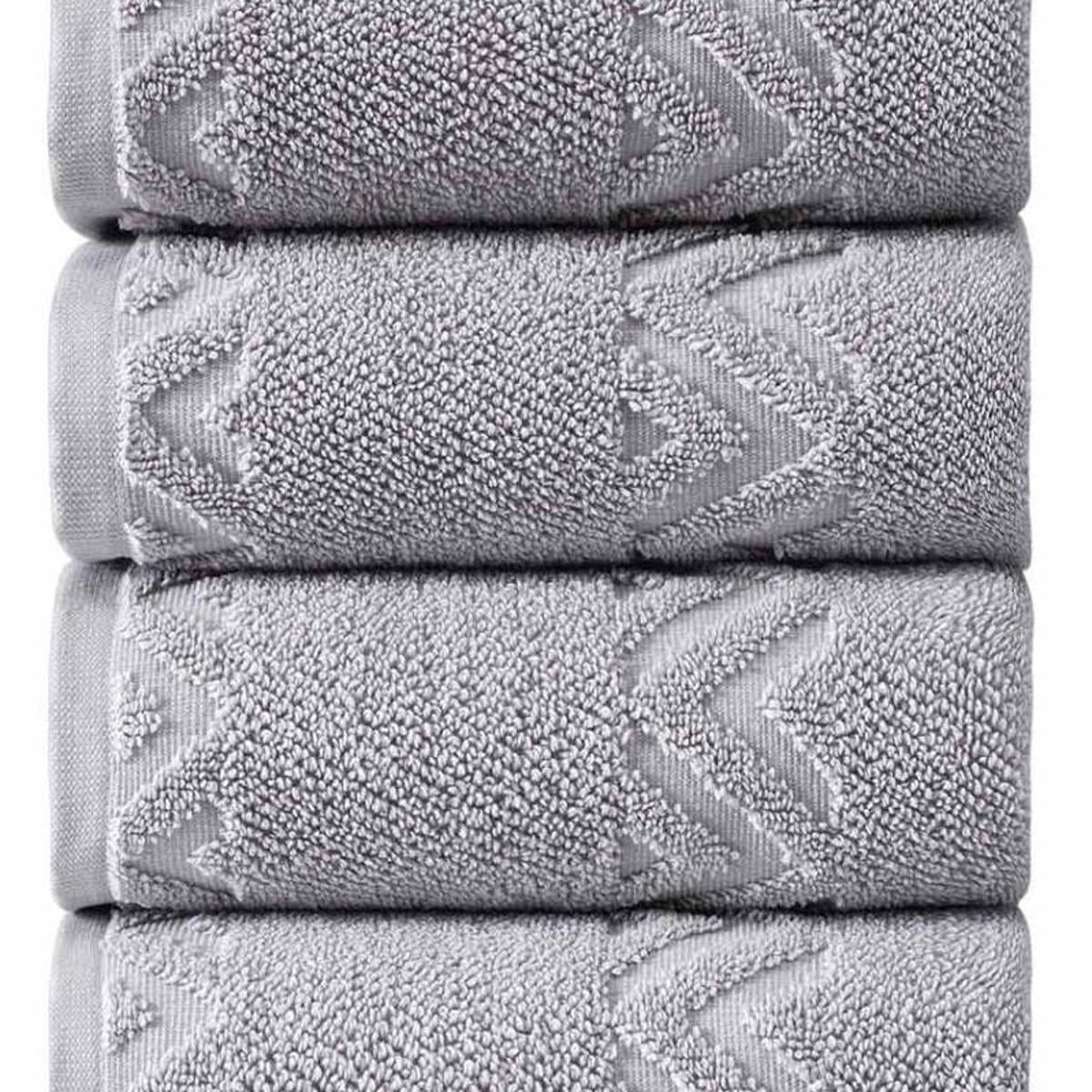 Light gray towel stack close-up showing looped texture and chevron zigzag embroidery.