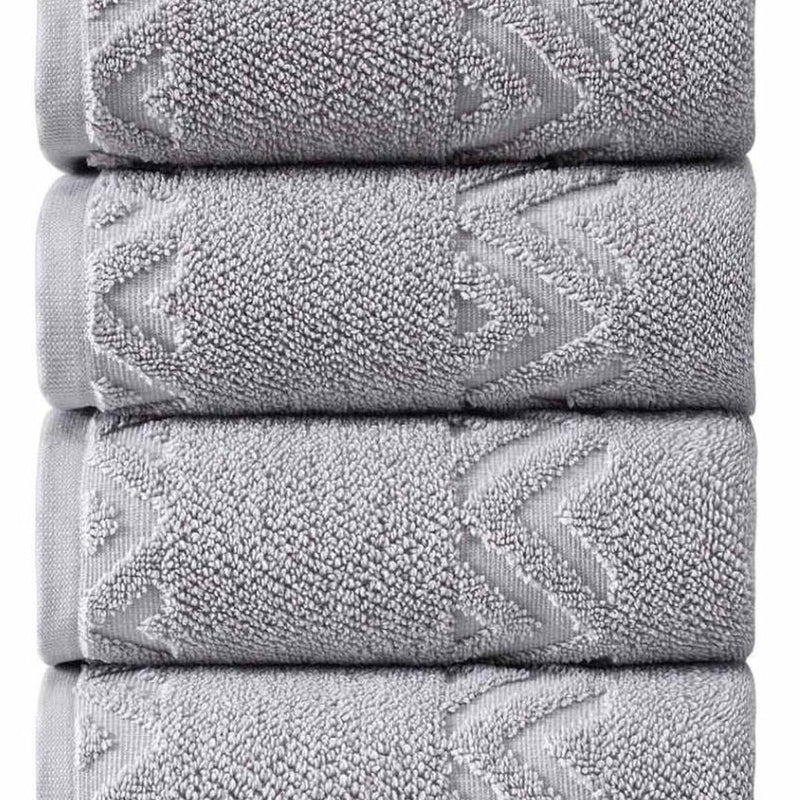 Light gray Turkish cotton hand towel stack close-up, textured zigzag geometric border.