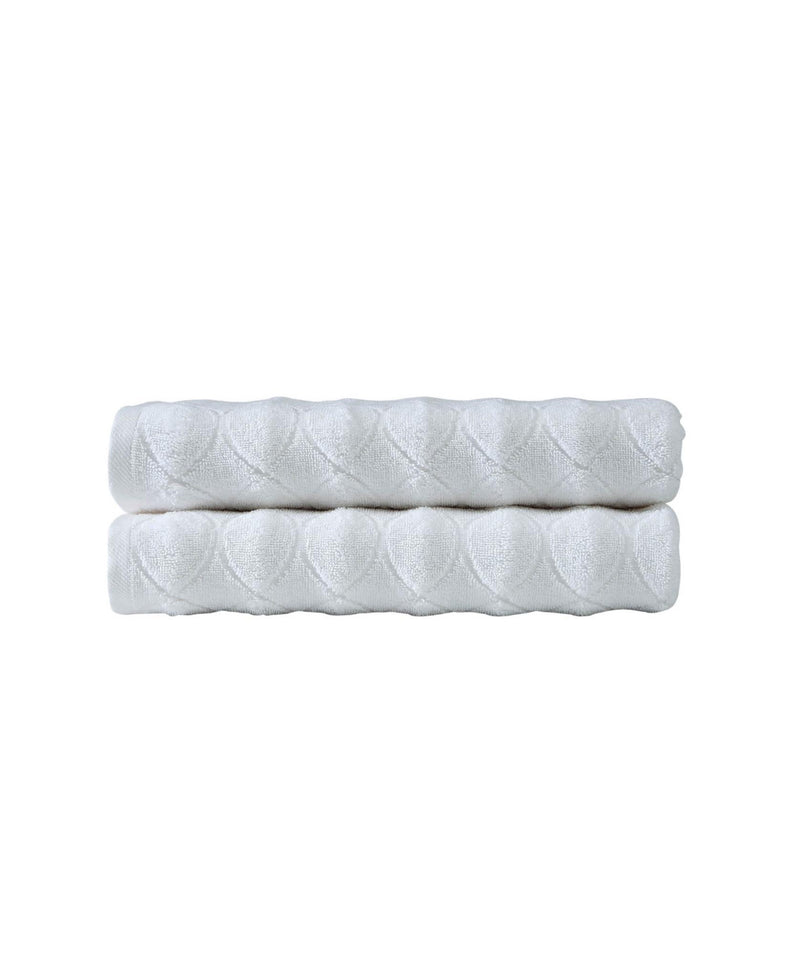 White bath towel pair with quilted diamond geometric pattern, stacked and folded