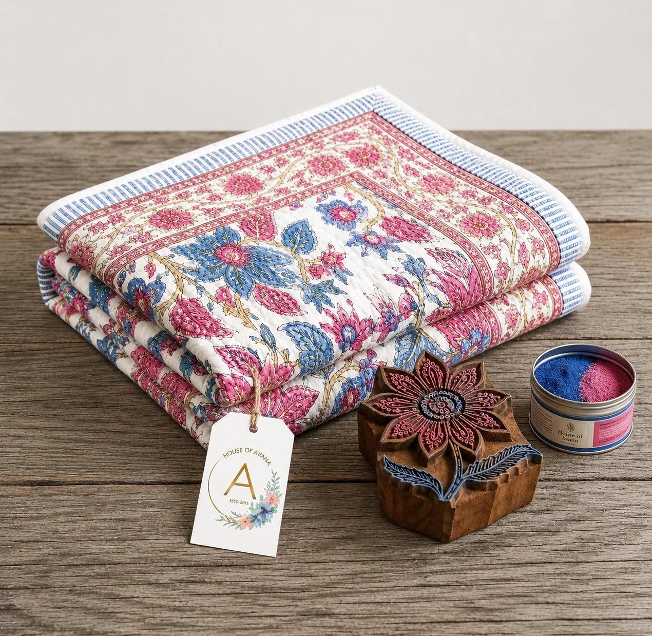 Rose and cream floral cotton comforter, folded with blue-trimmed striped edge