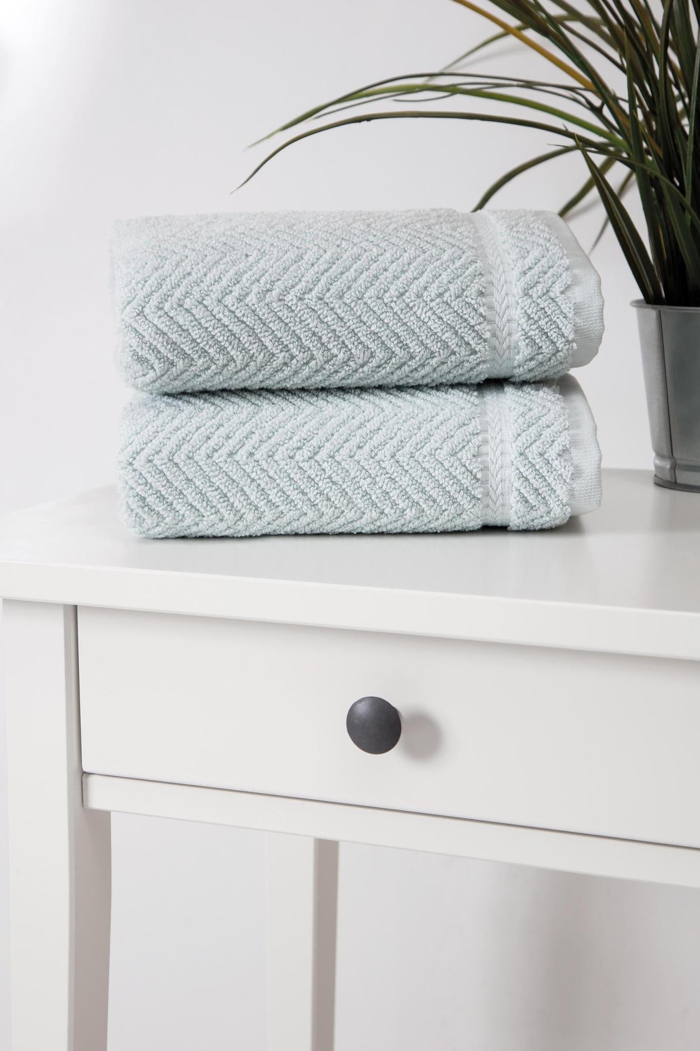 Two aqua chevron Turkish cotton hand towels on a bathroom vanity surface