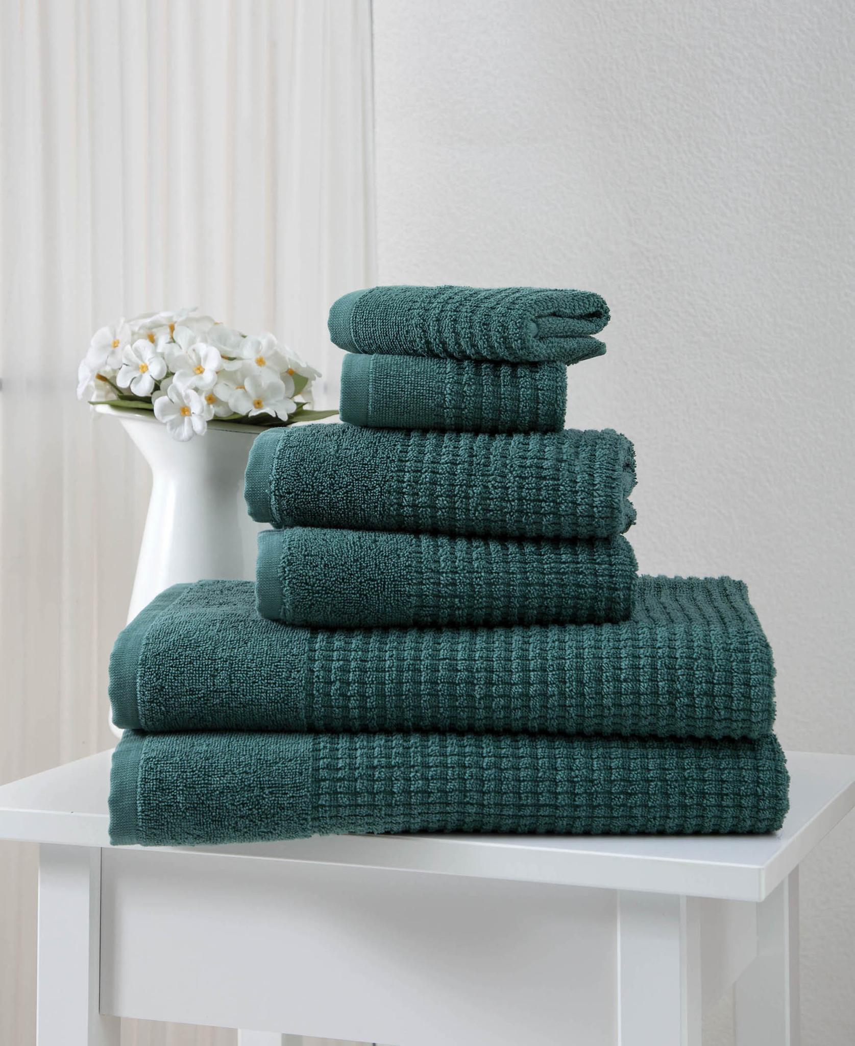 Stack of folded dark green textured Turkish cotton towels, neatly arranged