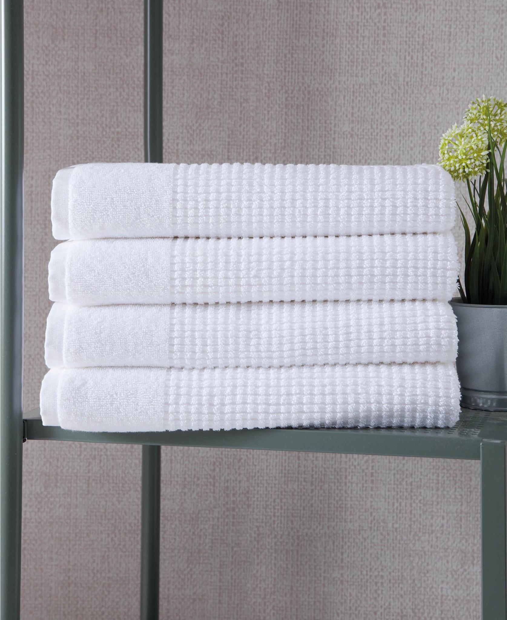 Set of four white bath towels, neatly folded stack