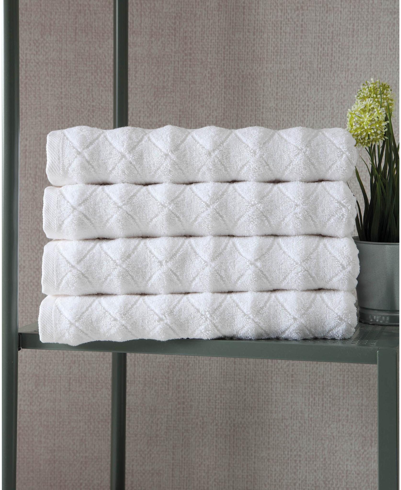 Set of four white Turkish cotton bath towels with geometric pattern, folded stack