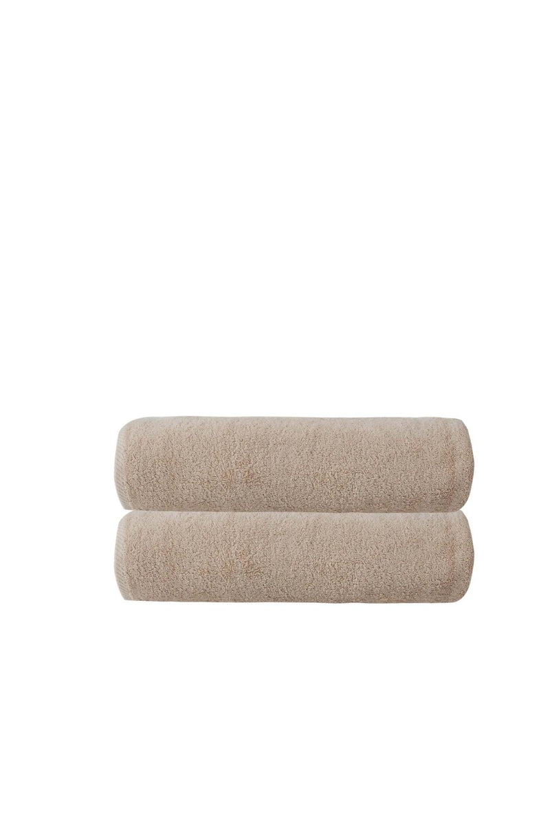Set of two beige Turkish cotton bath towels, rolled and stacked, textured loop pile