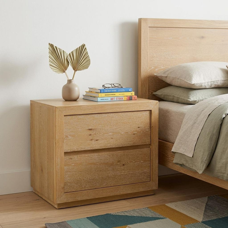 Oak wood two-drawer nightstand with rectangular drawer fronts, light natural finish