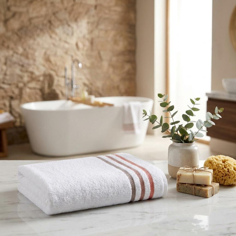 Folded white Turkish cotton bath towel with tan and coral stripe accents
