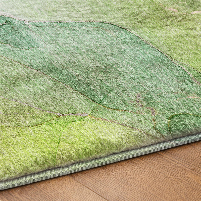 Green abstract shag area rug corner with gray border binding and textured surface detail.