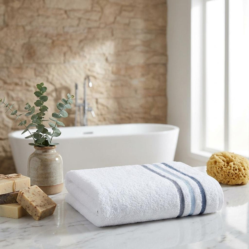 Rolled white bath towel with blue striped band, countertop set of two