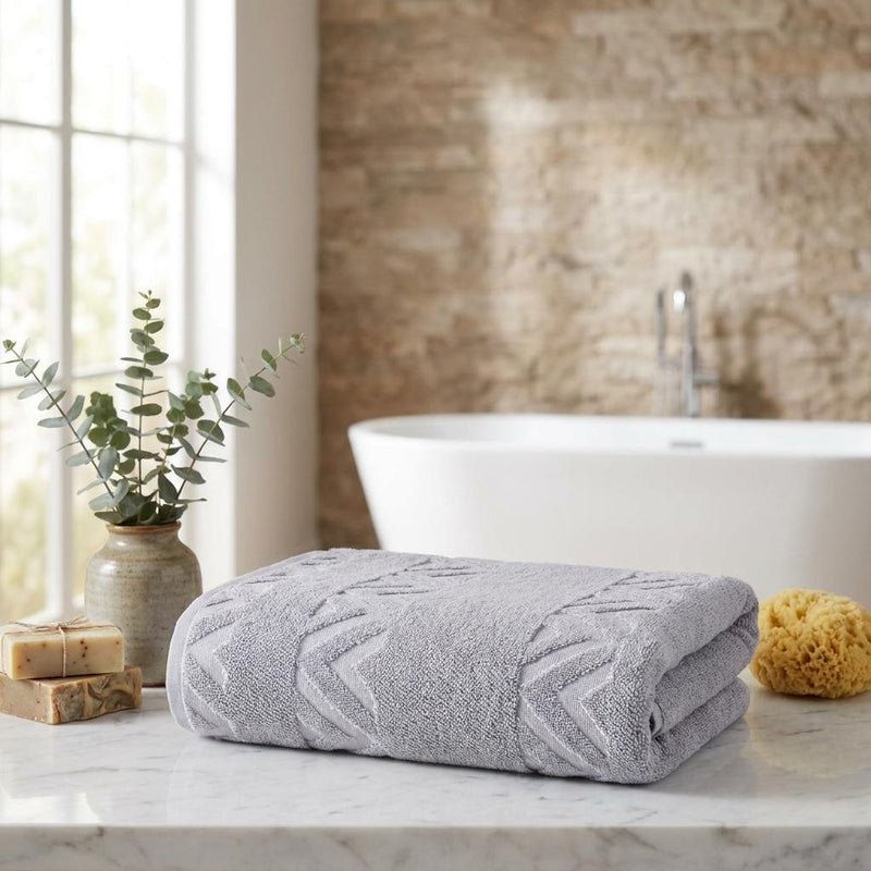 Light gray folded towel with geometric chevron pattern on bathroom counter