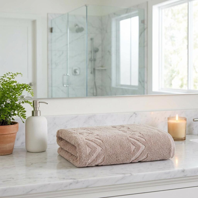Taupe bath sheet set with white chevron pattern folded on marble bathroom counter
