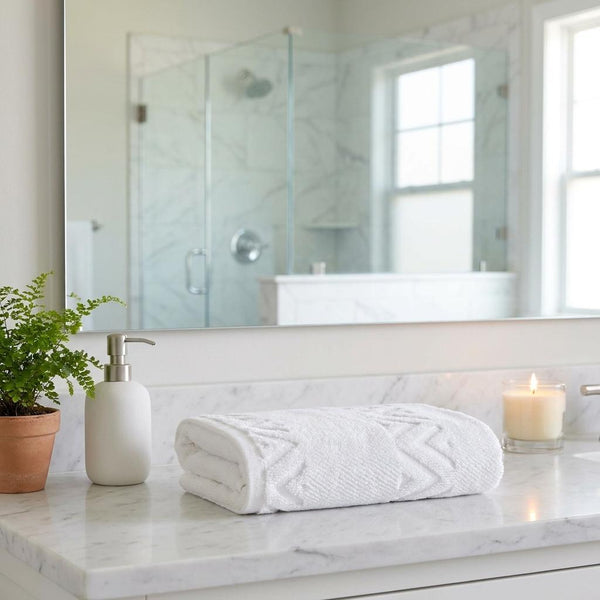 Set of two white hand towels with textured geometric zigzag pattern, rolled on surface
