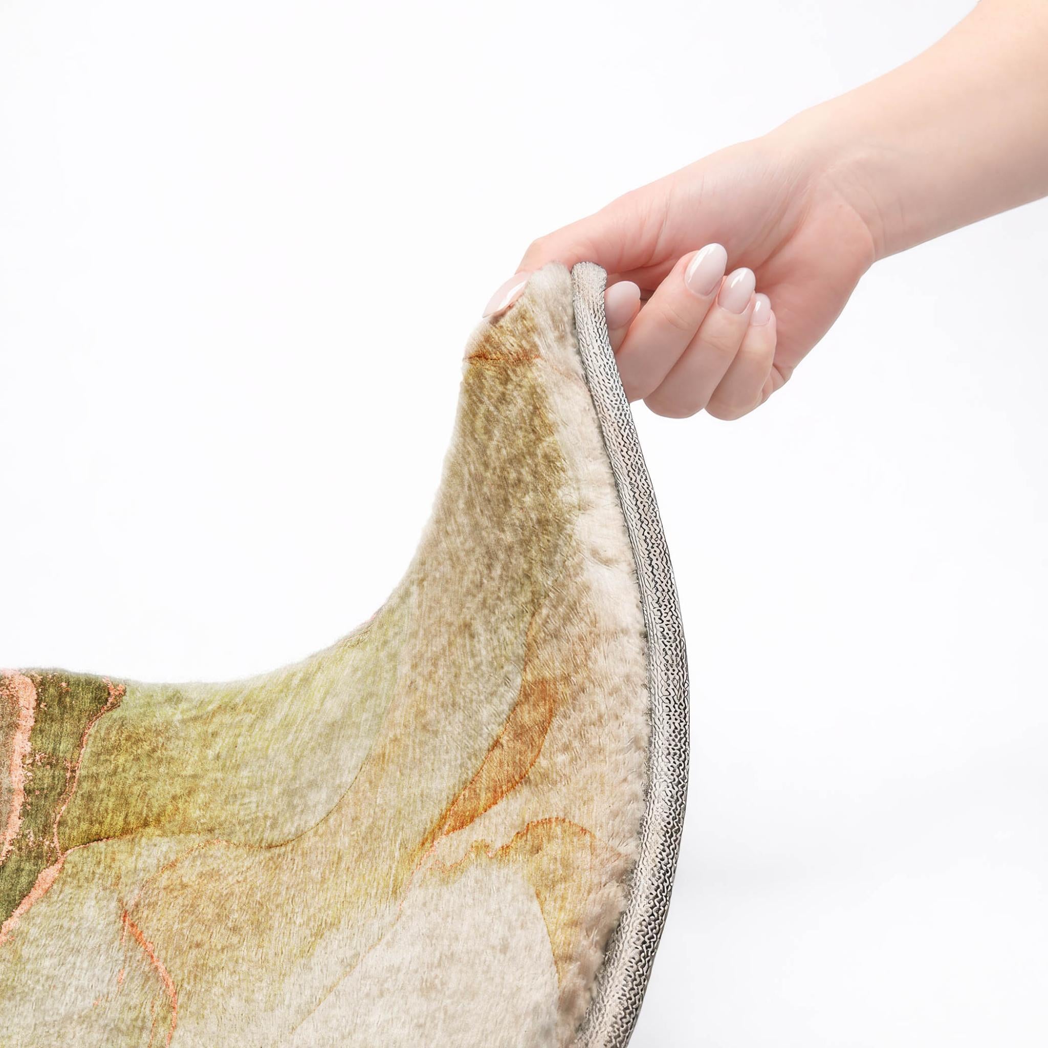 Hand holding edge of shag area rug; gray binding with abstract teal and coral pattern