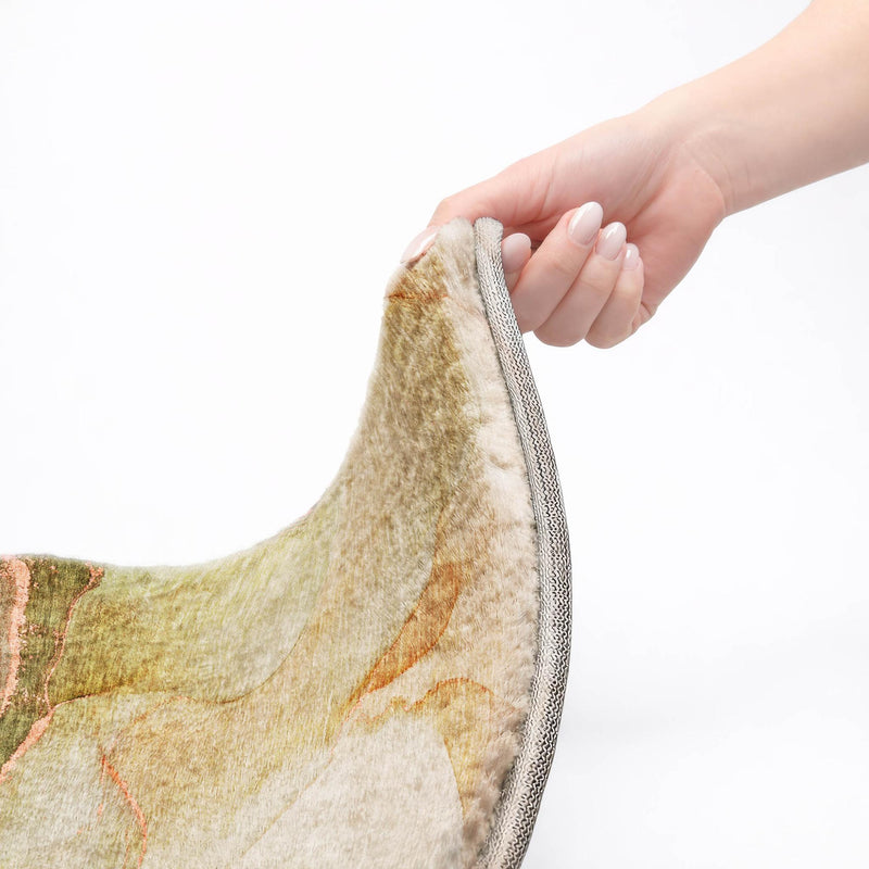 Hand holding edge of shag area rug; gray binding with abstract teal and coral pattern