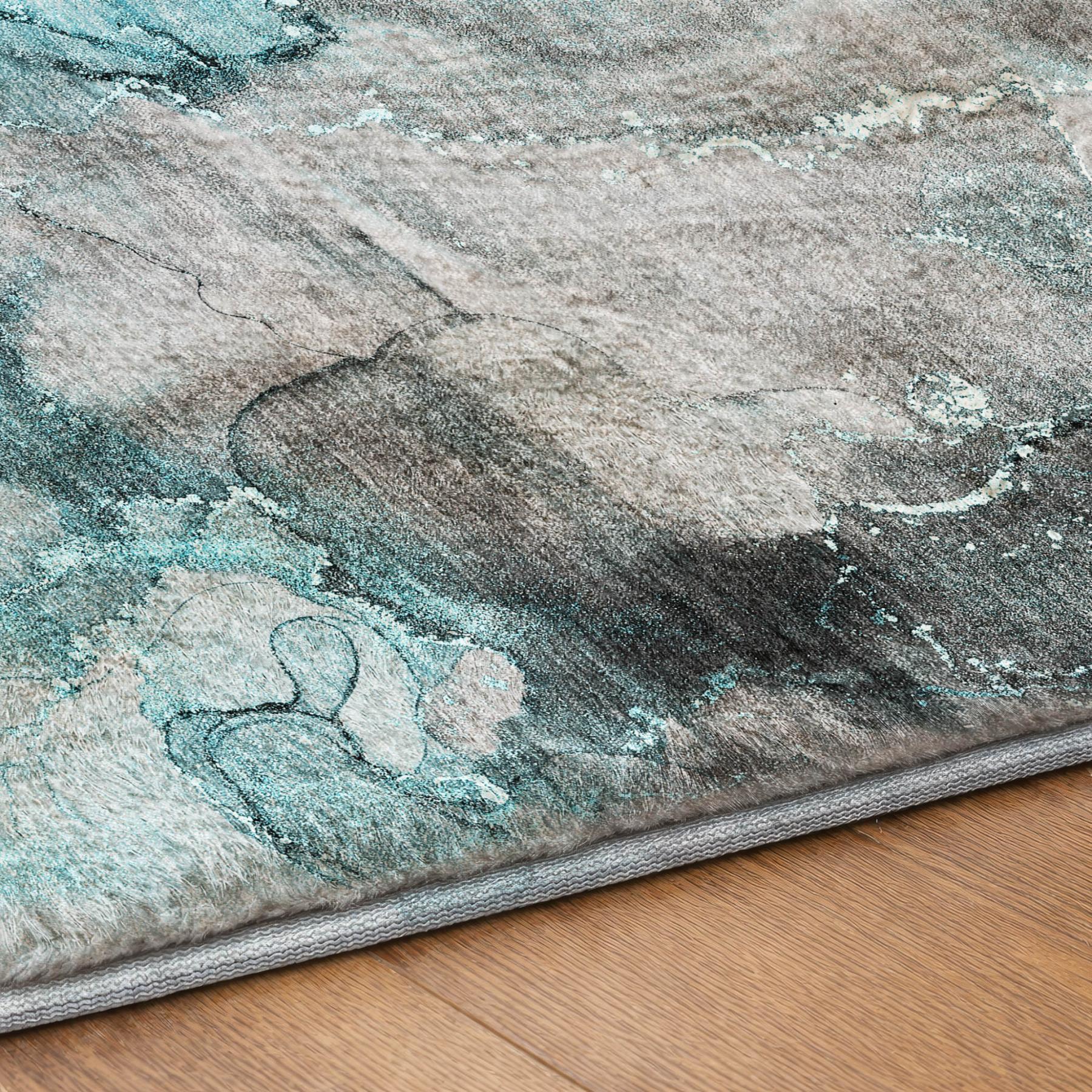 Abstract teal and gray shag rug corner with gray binding on wood floor