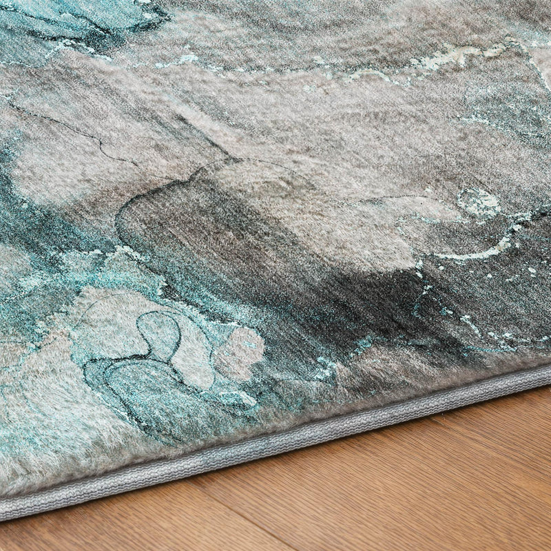 Abstract teal and gray shag rug corner with gray binding on wood floor