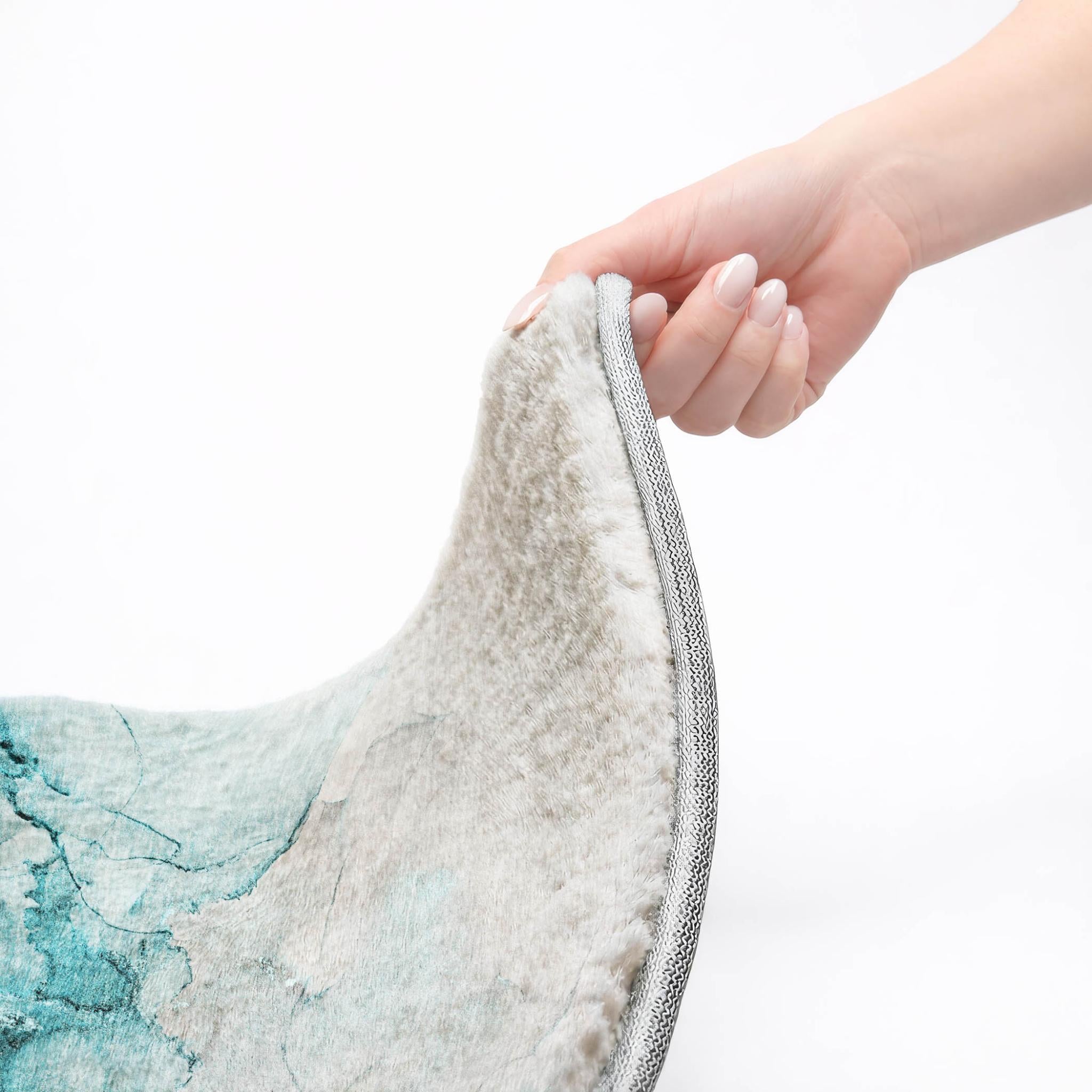Abstract shag rug edge with gray binding; hand grips the rim